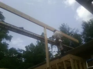 Carpenter setting a ridge beam over a new addition frame — Ice Dam Removal by Roofing Brothers in Hooker