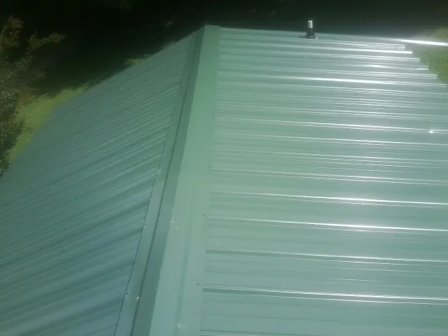 New green metal panels meeting at the ridge of a roof — Flat Roof Repair work by our crew in Hooker