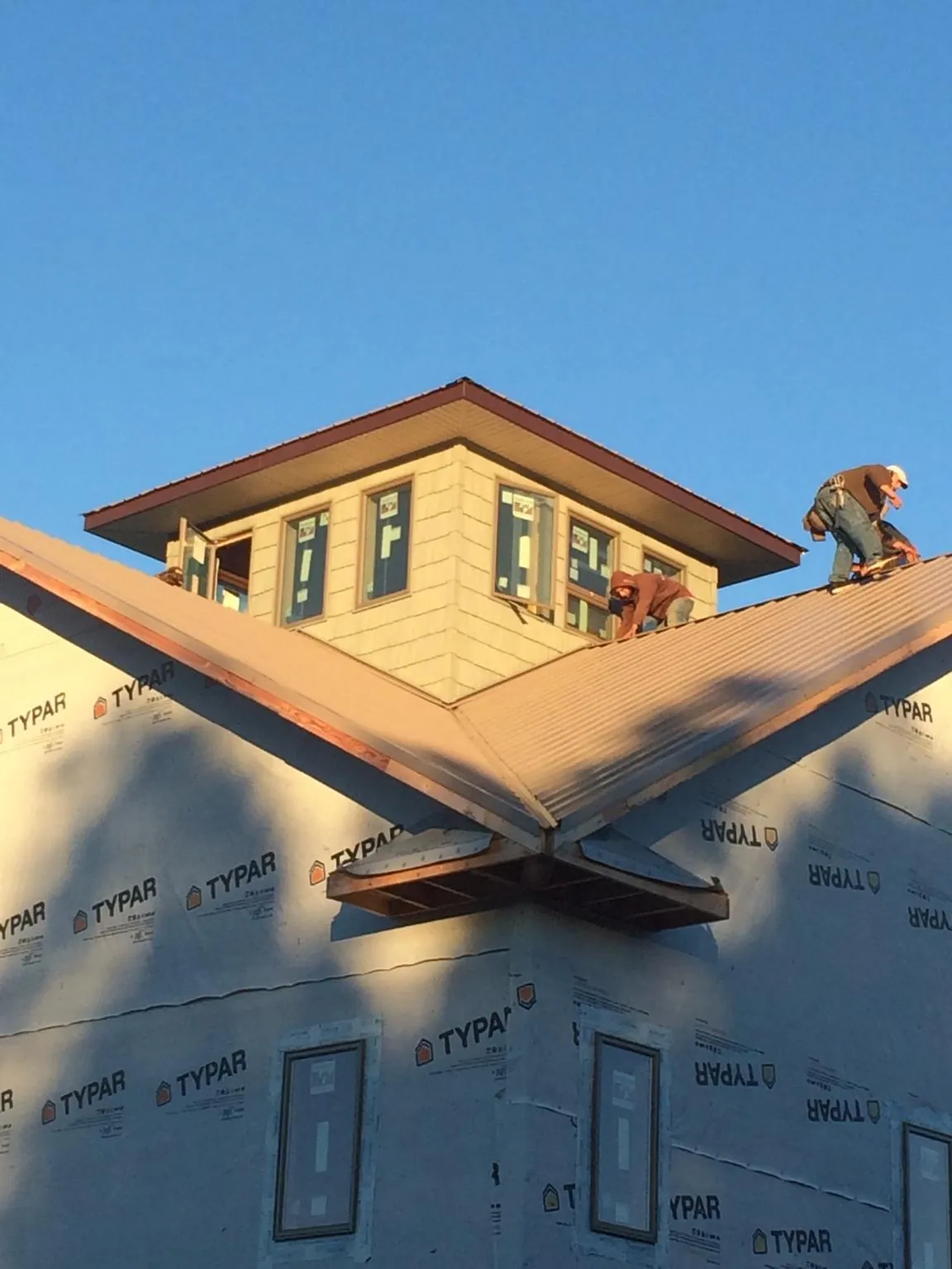 Roofers working around a rooftop cupola on a new metal roof at sunset — Roof Waterproofing in Hooker by Roofing Brothers